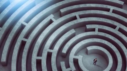 Confused businessman thinks how to find the right way to exit from a big maze.