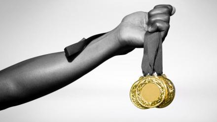 Hand holding three gold medals 