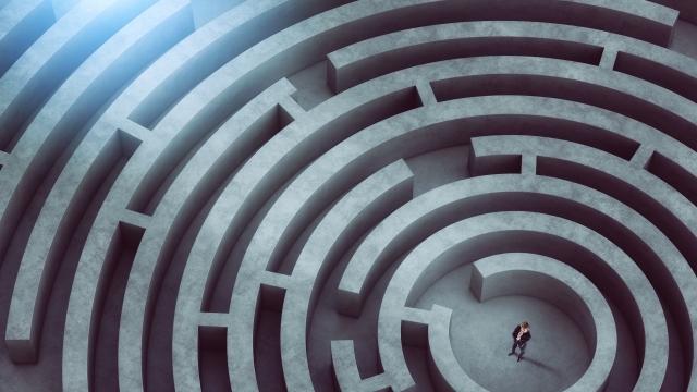 Confused businessman thinks how to find the right way to exit from a big maze.