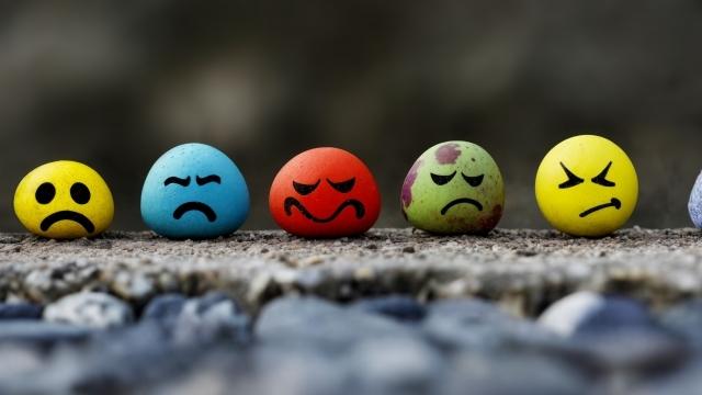 An assortment of emoji faces sitting on a rock. Angry, grumpy, sad upset, frustrated. A range of emotions. Different face expressions.