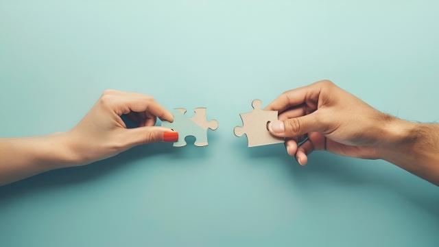 two hands holding on a puzzle piece each - to reflect the complexity of understanding free will and control.