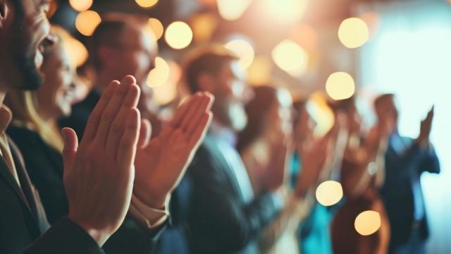 Image of Colleagues giving a standing ovation to an awarded team member, Team, blurred background