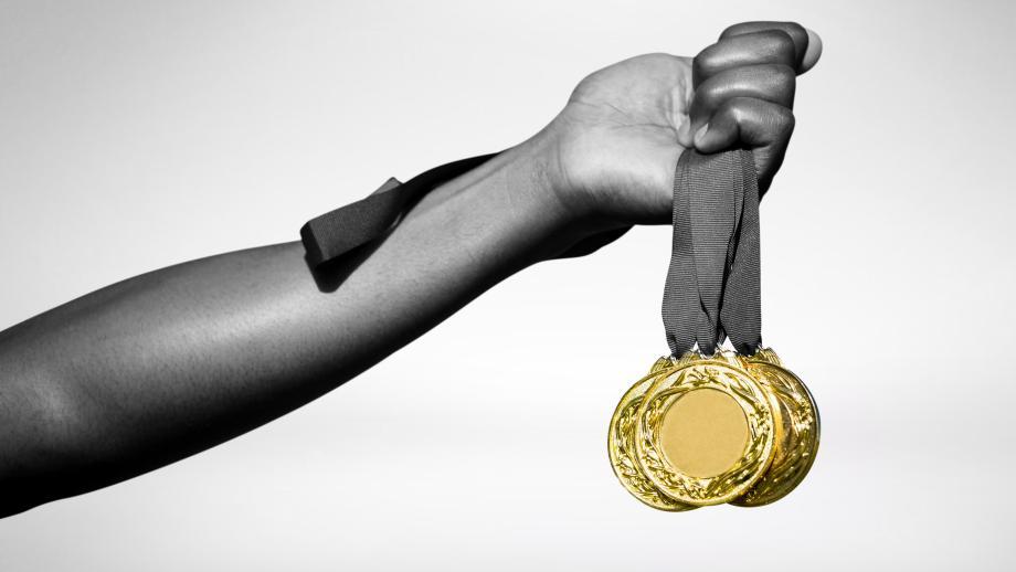 Hand holding three gold medals 